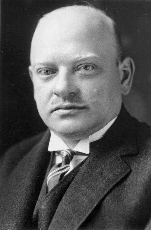 Black and white portrait of Gustav Stresemann with moustache, dark suit and striped tie